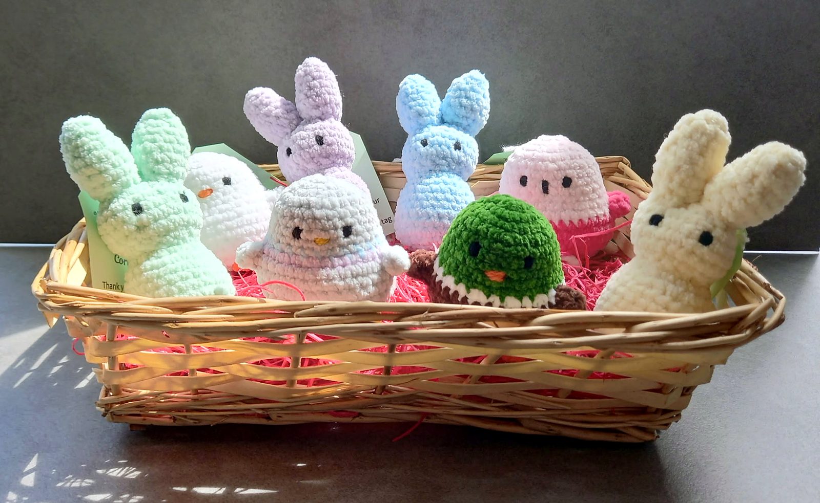 A basket of pastel crocheted bunnies, chicks and a duck